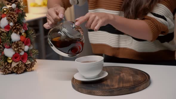 Close Up of Woman Pouring Tea From Kettle at Home