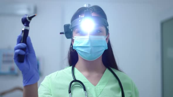 Front View Confident Caucasian Woman with Headlight Posing with Otoscope in Slow Motion