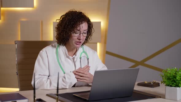 Female Doctor Consulting Patient Online at Laptop