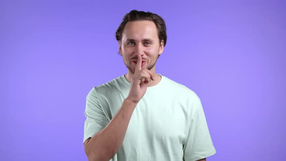 Smiling Man Holding Finger on Lips Over Violet Background