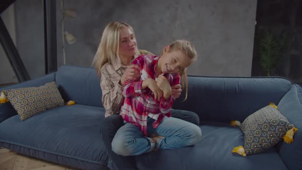 Joyful Mum and Cute Daughter Bonding on Sofa