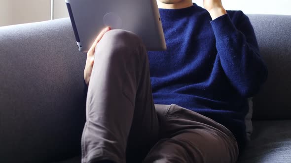 Man talking on mobile phone while using digital tablet in living room 4k