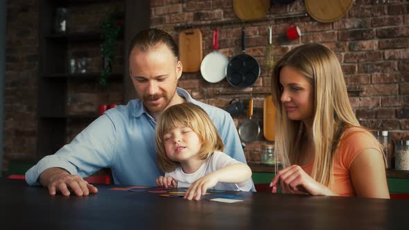 Young Mother Father and Their Little Boy in Casual Outfit are Smiling and Playing a Game with