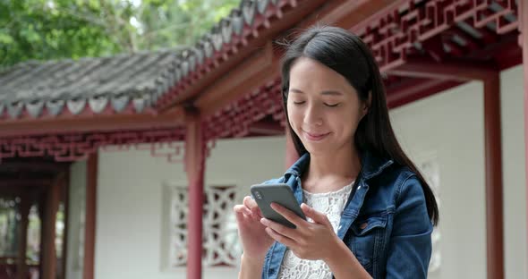 Woman using mobile phone in traditional Chinese garden