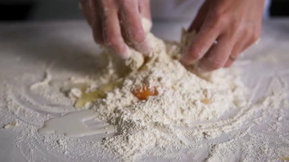 Closeup View of Female Hands Mixing Flour with Eggs and Milk on the Kitchen Surface