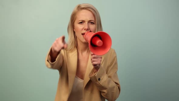 Beautiful woman in jacket with megaphone on blue background