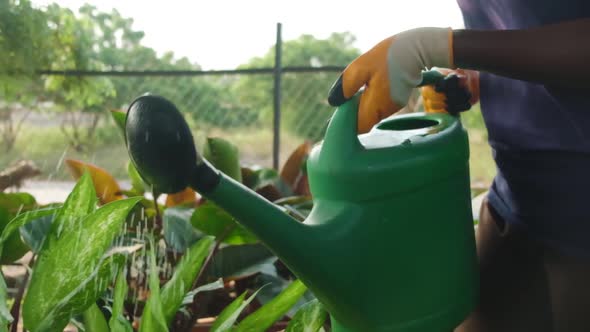 lift green watering can to water plants slow