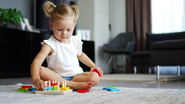 Cute Caucasian Little Girl Playing on the Floor at Home with Eco Wooden Toys