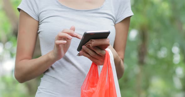 Housewife using cellphone and holding plastic bags