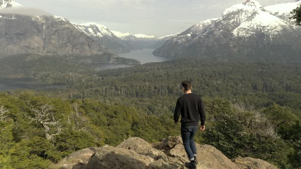 Aerial shot of an unrecognizable man reaching a viewpoint of Patagonian lakes and mountains