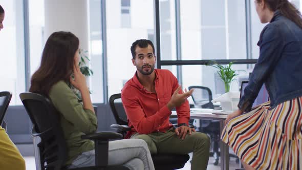 Diverse group of work colleagues sitting at desk and discussing