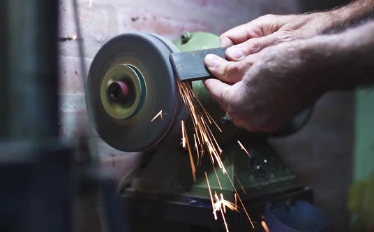 Worker Man Grinding Metal and Making Sparks With The Bench Grinder