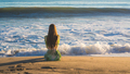 Attractive young woman sitting on the beach looking at the ocean - PhotoDune Item for Sale