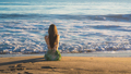 Attractive young woman sitting on the beach looking at the ocean - PhotoDune Item for Sale