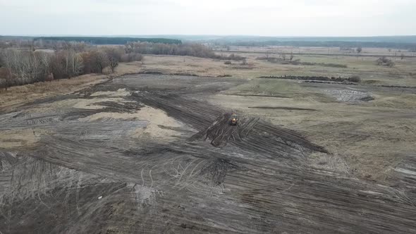 Stunning View of a Huge Field and an Excavator Driving in the Dirt