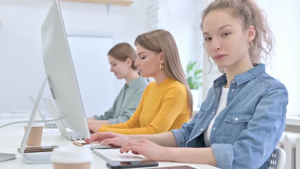 Young Woman Working on Desktop and Smiling at the Camera