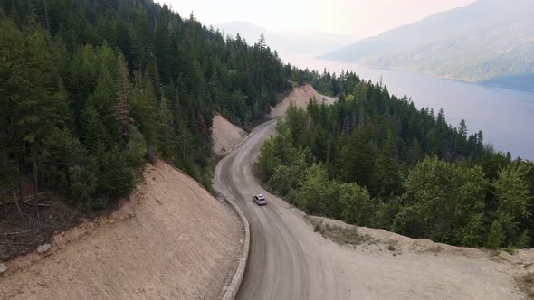 Silver car leaving for an adventurous drive through the vast pine forests of British Columbia. Aeria