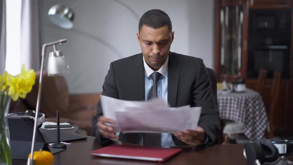 Middle Shot of Overworked African American Man Analyzing Graphs and Screaming Sitting at Table in