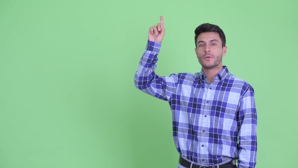 Happy Young Handsome Hispanic Man Talking While Pointing Up