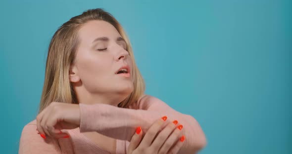 Lady with Long Loose Fair Hair Sneezes Into Upper Sleeve