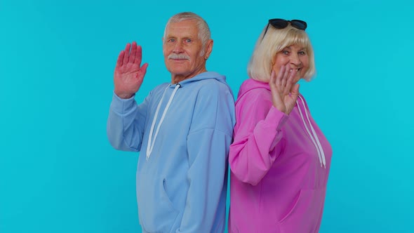 Elderly Granny with Grandfather Turning Smiling at Camera Waving Hands Gesturing Hello or Goodbye