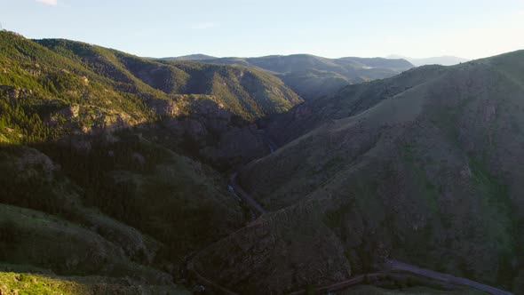 Aerial Drone Shot Of Shadowy Mountain Valley During Beautiful Golden Hour Sunset. Drone Flying Backw