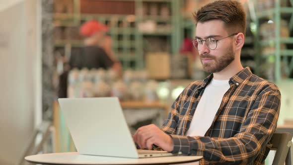 Professional Young Man Using Laptop in Cafe 