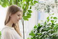 side portrait of a teenager girl in a modern house with lots of green plants - PhotoDune Item for Sale