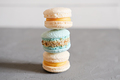 stack of french macaron cookies on a grey table. pastel yellow and turquoise colored macaroons - PhotoDune Item for Sale