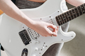 female artist playing electric guitar performing a song. crop view. woman with white guitar - PhotoDune Item for Sale
