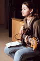 young woman playing bass guitar and reading chord notes at band rehearsal. vertical size. - PhotoDune Item for Sale