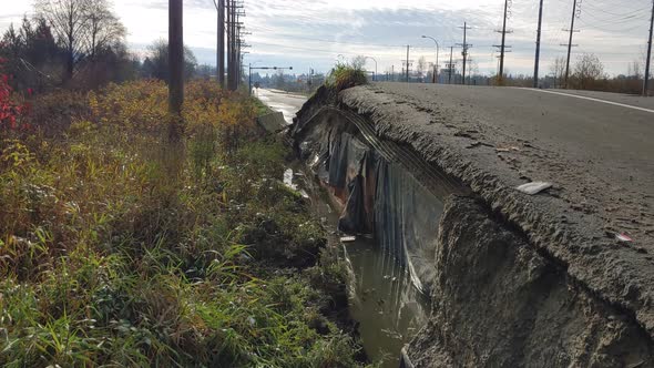 Damaged road from water flowing underneath in a flood at Abbotsford, BC, Canada - dolly shot