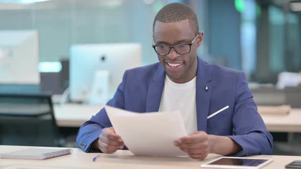 African Businessman Celebrating Success While Reading Documents