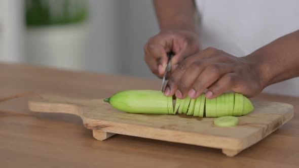 Close Up Shot of Hands of African Man Cutting Cucumbers on Cutting Board