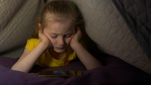 Little Girl With Phone On Bed