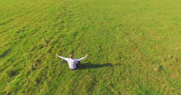 Low Orbital Flight Around Man on Green Grass with Notebook Pad at Yellow Rural Field.