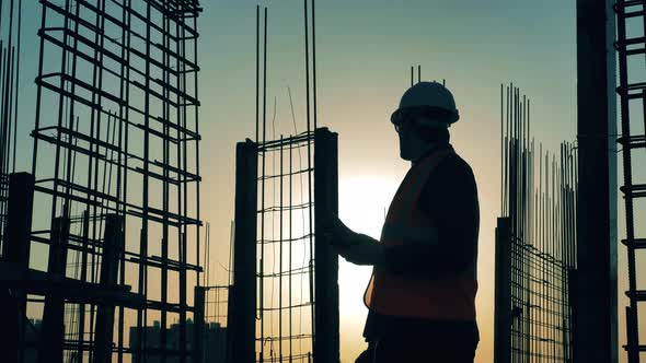 Construction Worker Is Making Calculations on a Roof at Sunset