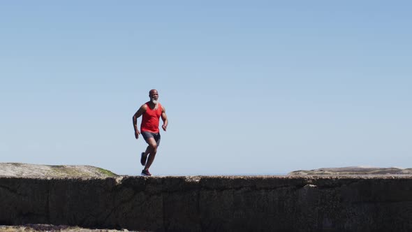 Senior african american man exercising running on rocks by the sea