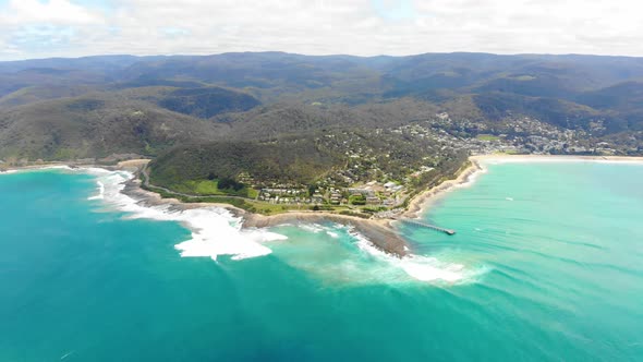 High Aerial bird's eye view over the aqua ocean flying towards land.