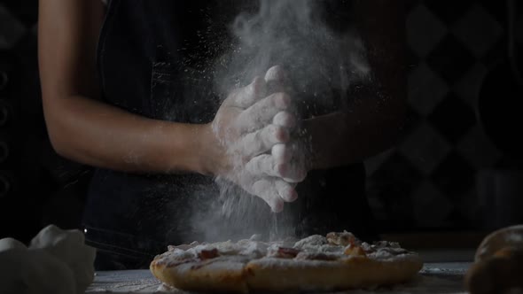 Slow motion of woman hands sifting flour on pizza