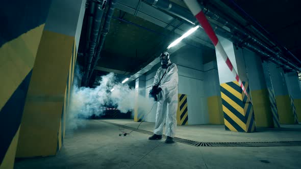 A Person in a Hazmat Suit Is Decontaminating Storage Space. Worker Disinfecting Indoors Using