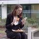 Businesswoman Browsing Smartphone and Snacking with Sandwich in Yard - VideoHive Item for Sale