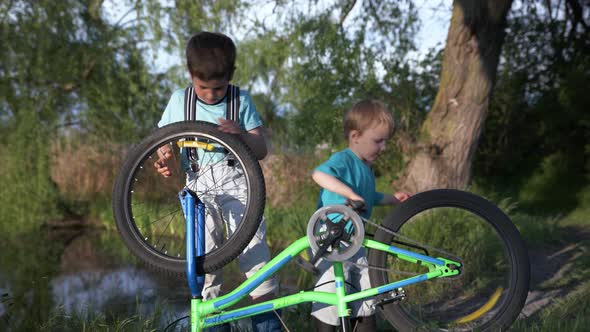 Attractive Curious Boys Spin Wheels and Pedals of Bicycle While Having Fun Outdoors By River