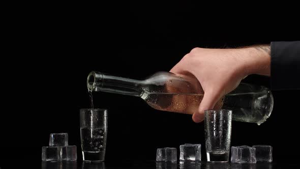 Two Hands with Glasses of Vodka Making Cheers Raising Toast on Black Background with Ice Cubes