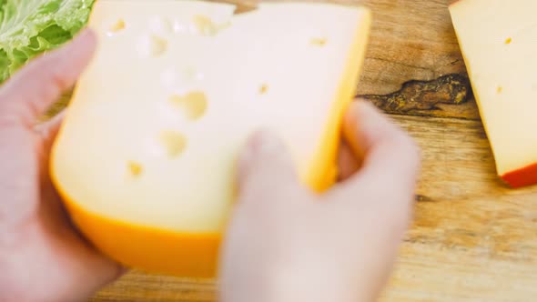 The Woman Holds in Her Hands a Piece of Cheese with Holes