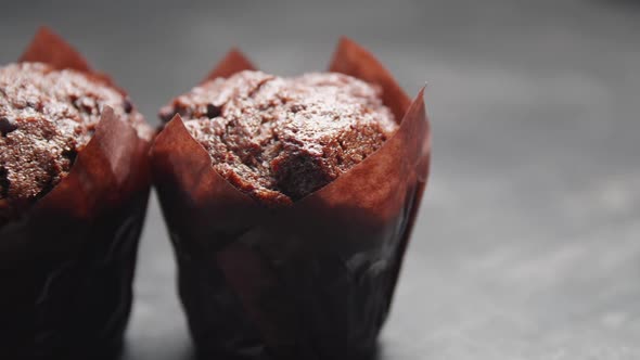 Ready-to-eat сhocolate muffins with crispy top on the gray background.