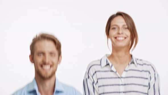 Beautiful Caucasian Couple Alternately Squating Smiling and Laughing on White Background