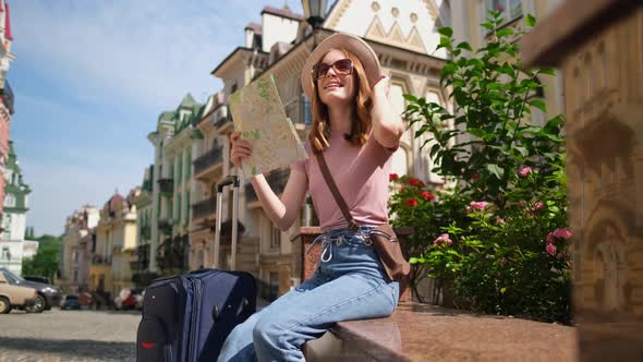 Beautiful Young Woman Tourist Pleasant with City Map and Suitcase in the City Center