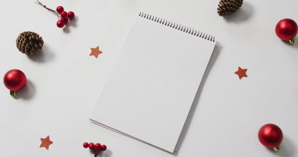 Video of red christmas decorations with notebook on white background