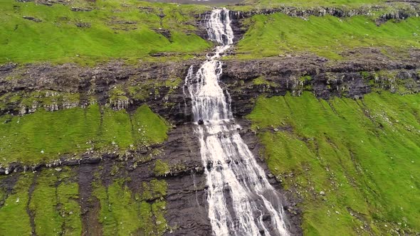 Aerial view of breathtaking waterfall crossing rock mountain, Faroe Island.